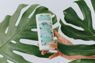 Hand holding Lily of the valley deodorant stick with leaves in the background